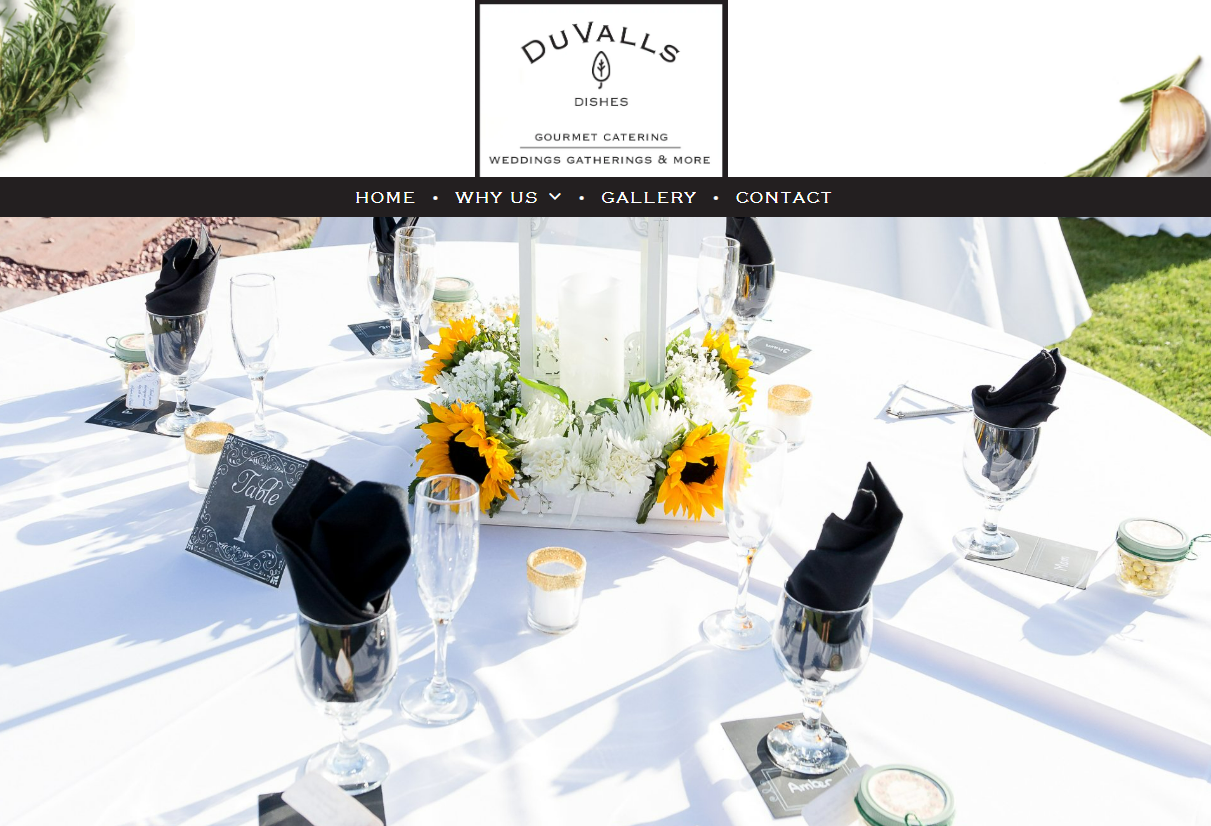 Formal dining table set for an event; sunflowers, candles, black napkins, white tablecloth.