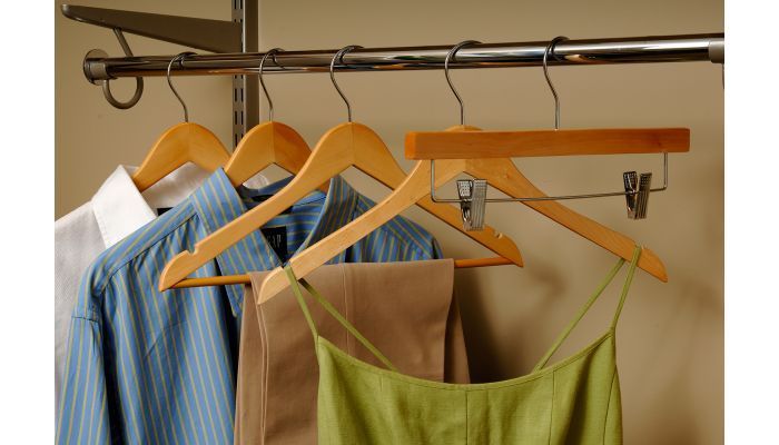 Clothes hanging in a closet: white shirt, blue shirt, tan pants, and green dress.