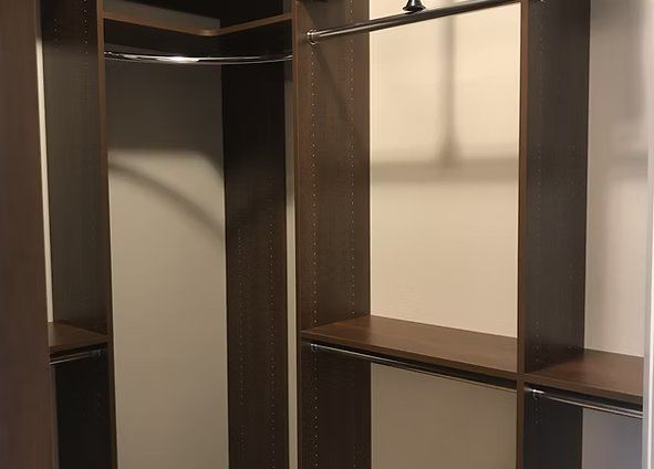 Empty dark wood closet with shelves and rods.