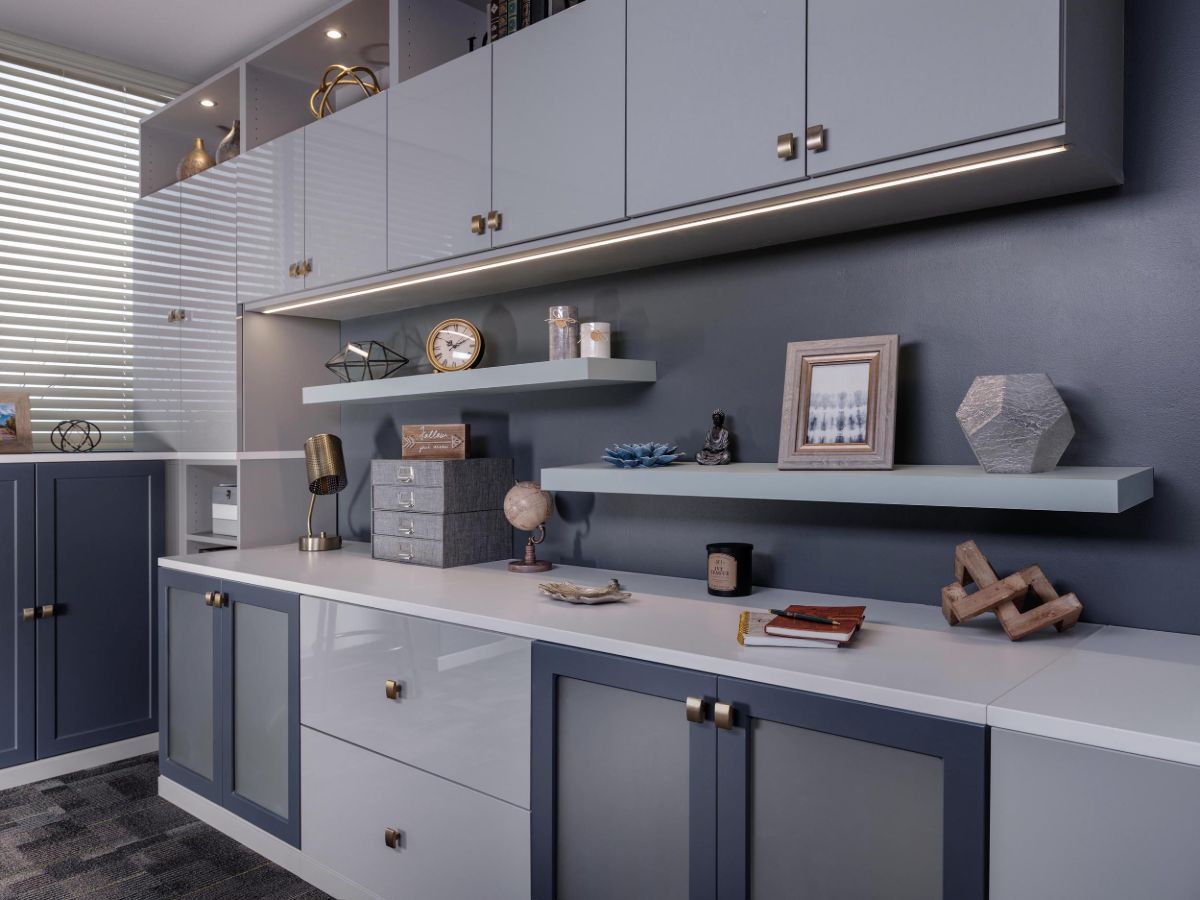 Home office with gray cabinets, shelves, and desk against a dark blue wall.