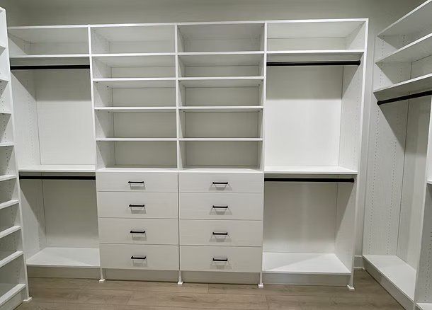 White custom closet organization system with shelves, drawers, and hanging rods.