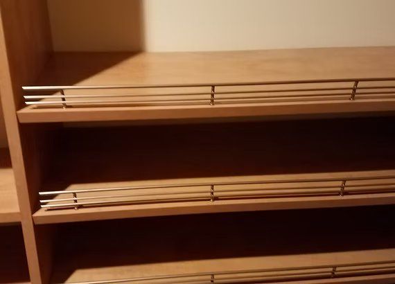 Wooden closet shelves with chrome safety bars.
