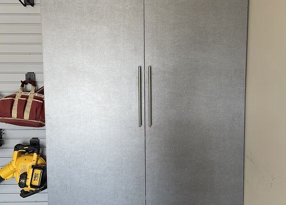 Silver closet doors with vertical handles; tools hang on the left side.