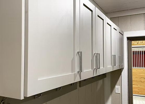 White overhead cabinets with silver handles, mounted on a wall near a doorway.