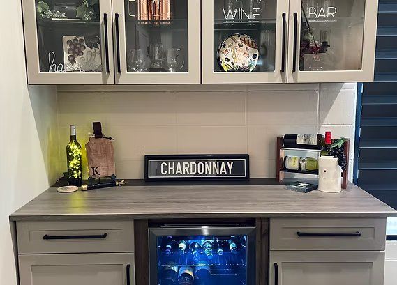A built-in home bar with a wine cooler, cabinets, and a "Chardonnay" sign.