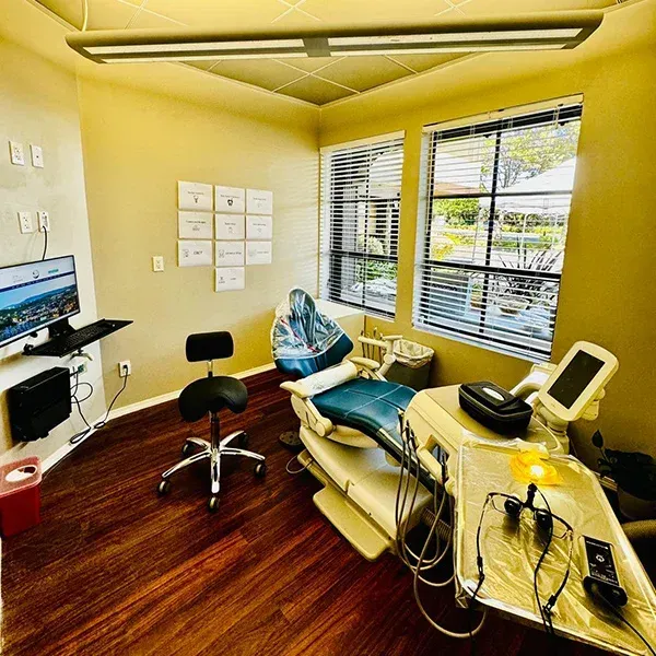 A dental office with a dental chair and a computer.