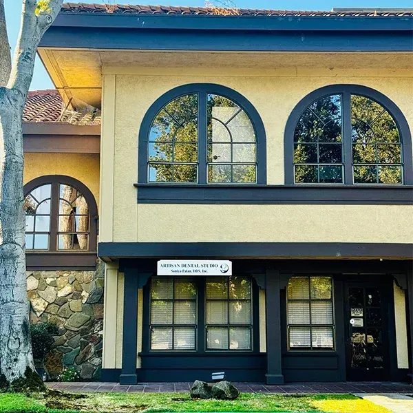 A large building with arched windows and a tree in front of it.