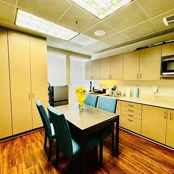 A kitchen with a table and chairs and a vase of flowers