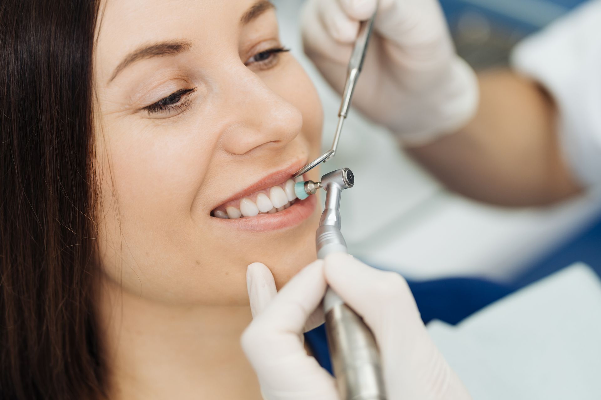 A woman is sitting in a dental chair while a dentist holds a model of a skull.