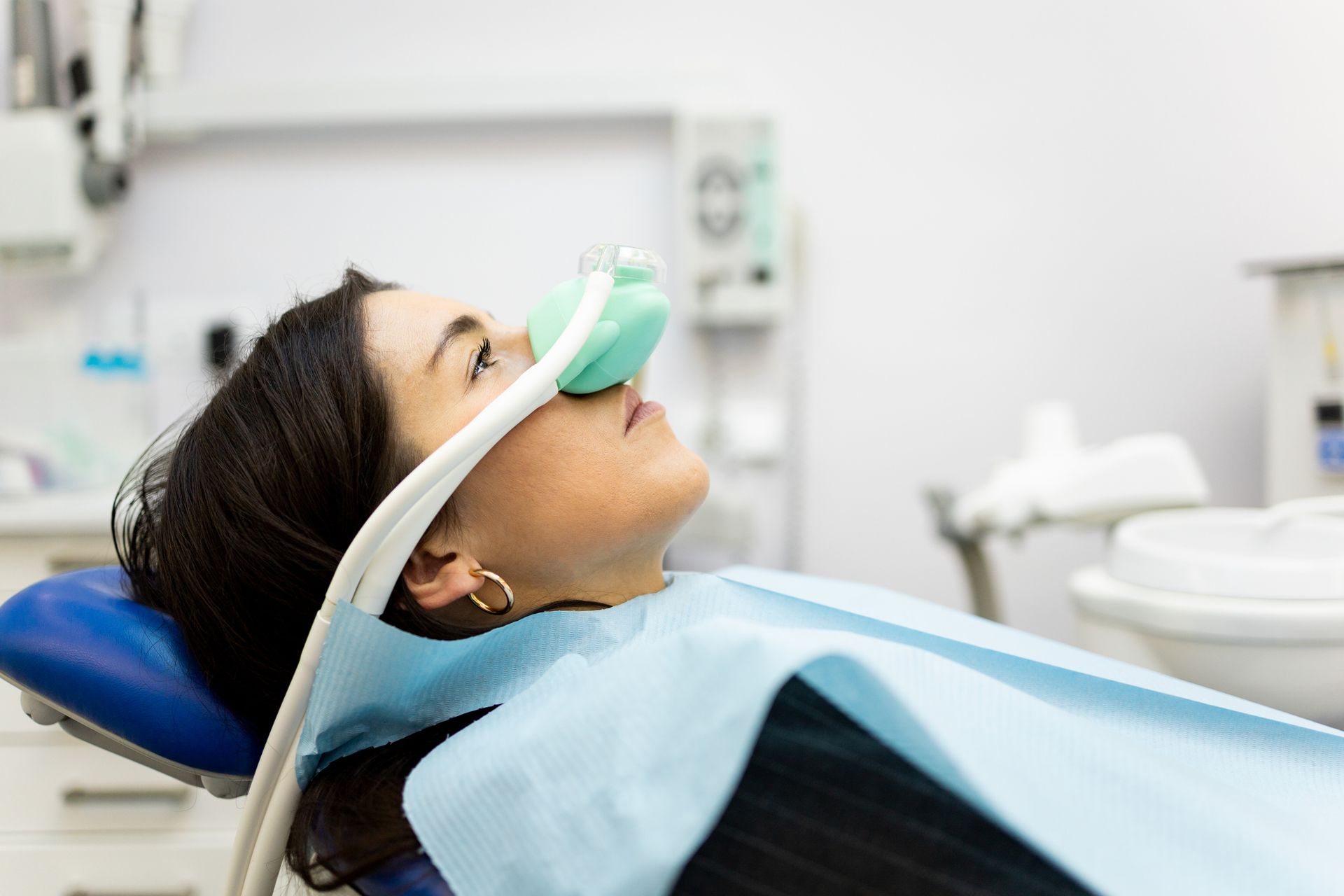 A woman is laying in a dental chair with an oxygen mask on her face.