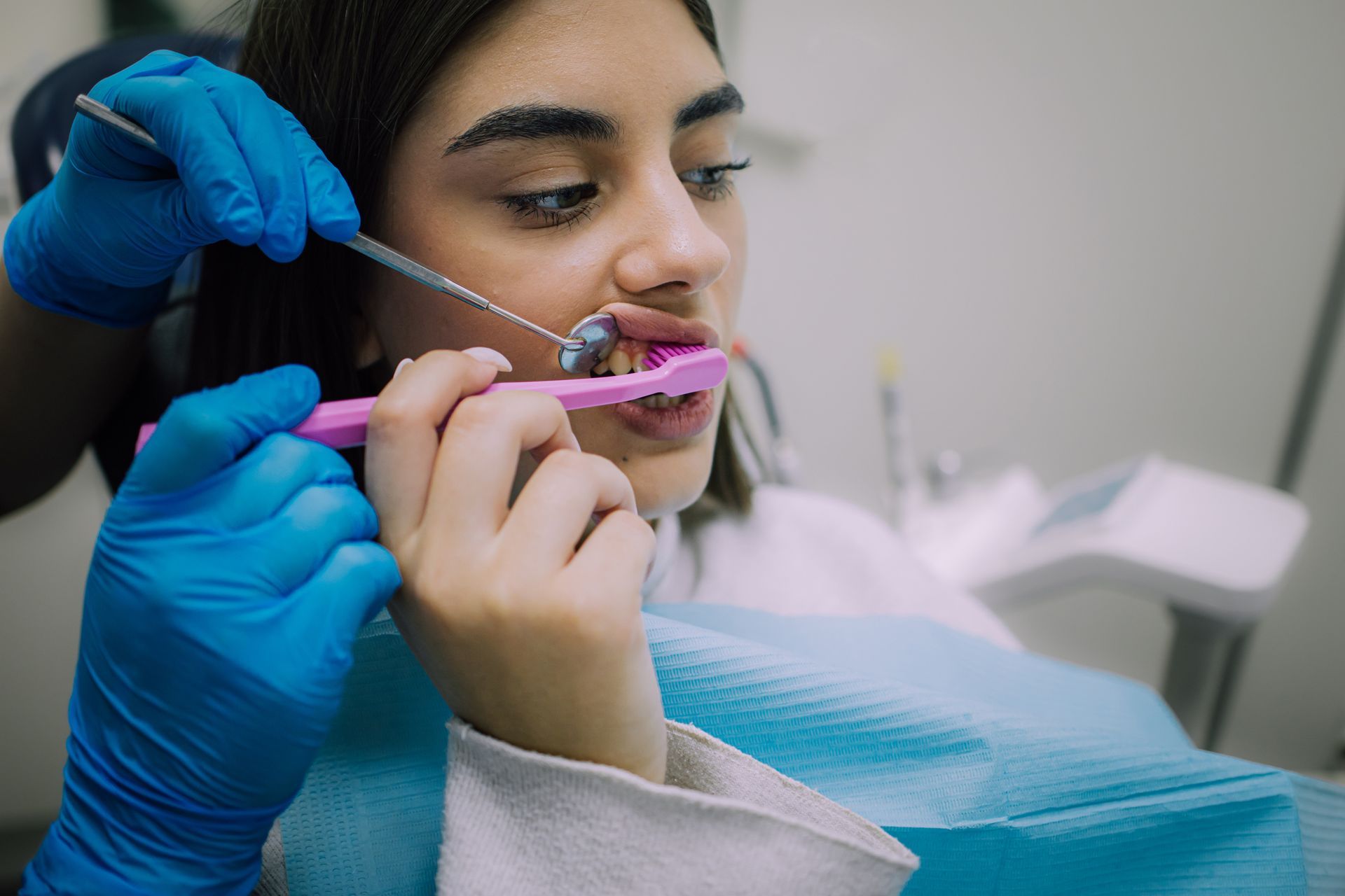 A woman is sitting in a dental chair while a dentist holds a model of a skull.