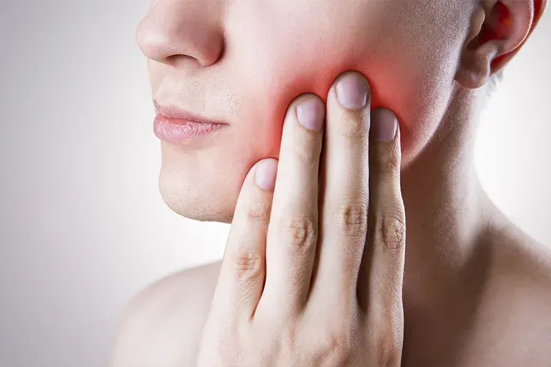 A woman is holding her face in pain because of a toothache.