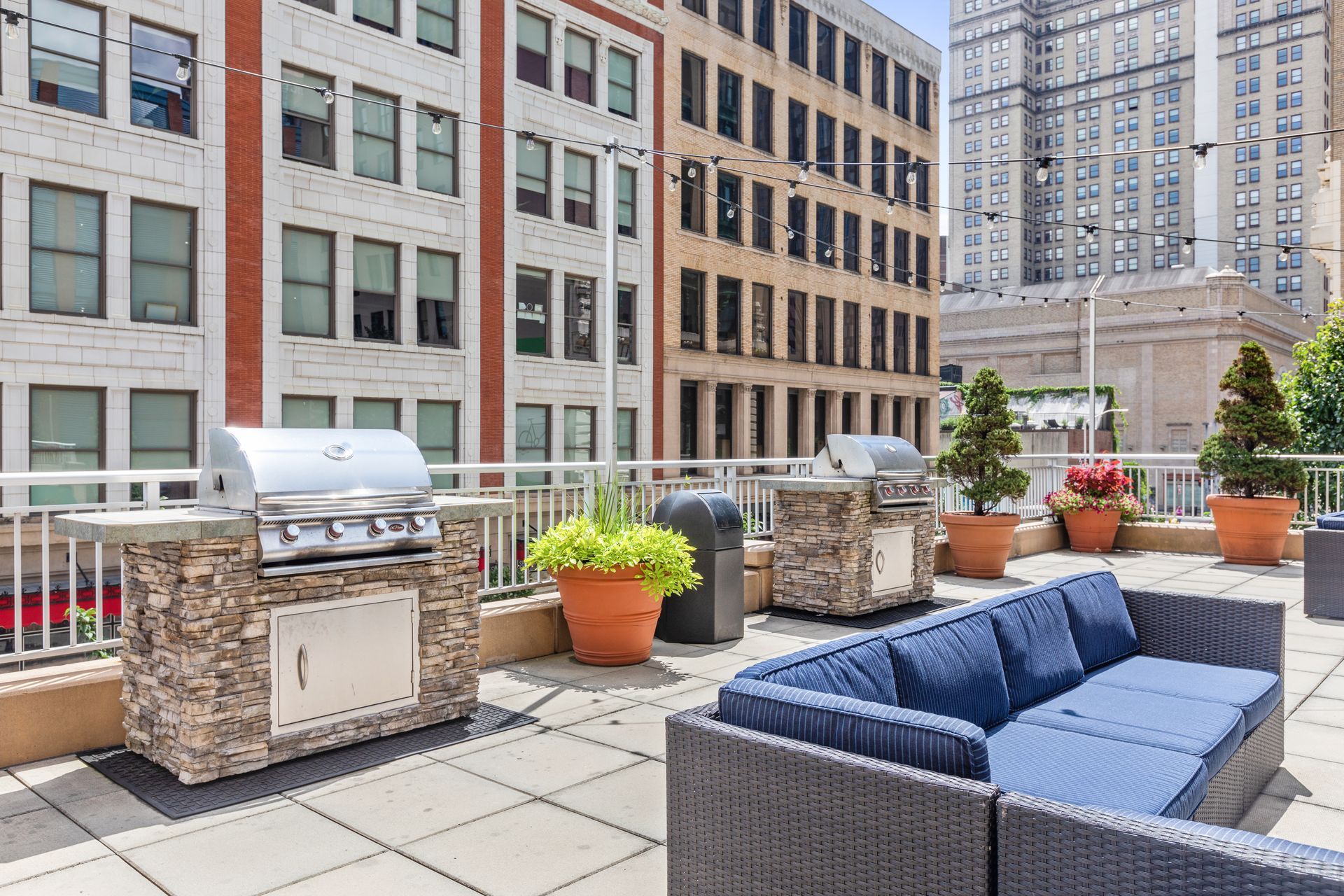 There is a couch and a grill on the roof of a building.