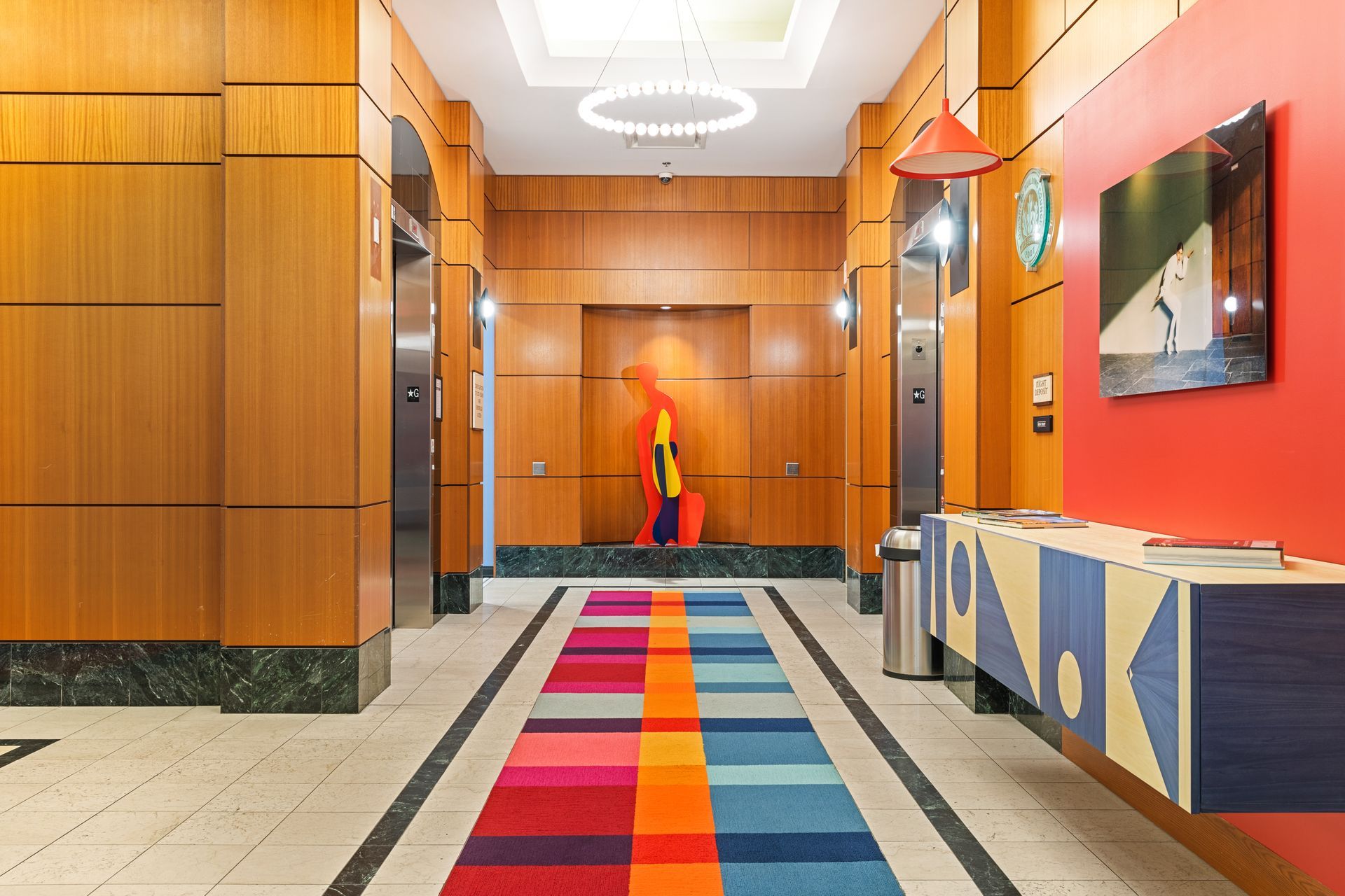 A hallway with a colorful rug and a painting on the wall.