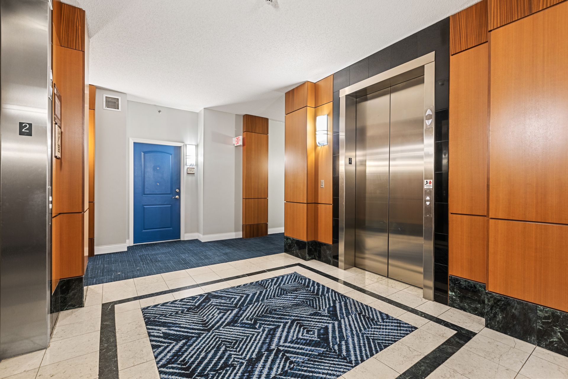 A hallway with two elevators and a blue door.