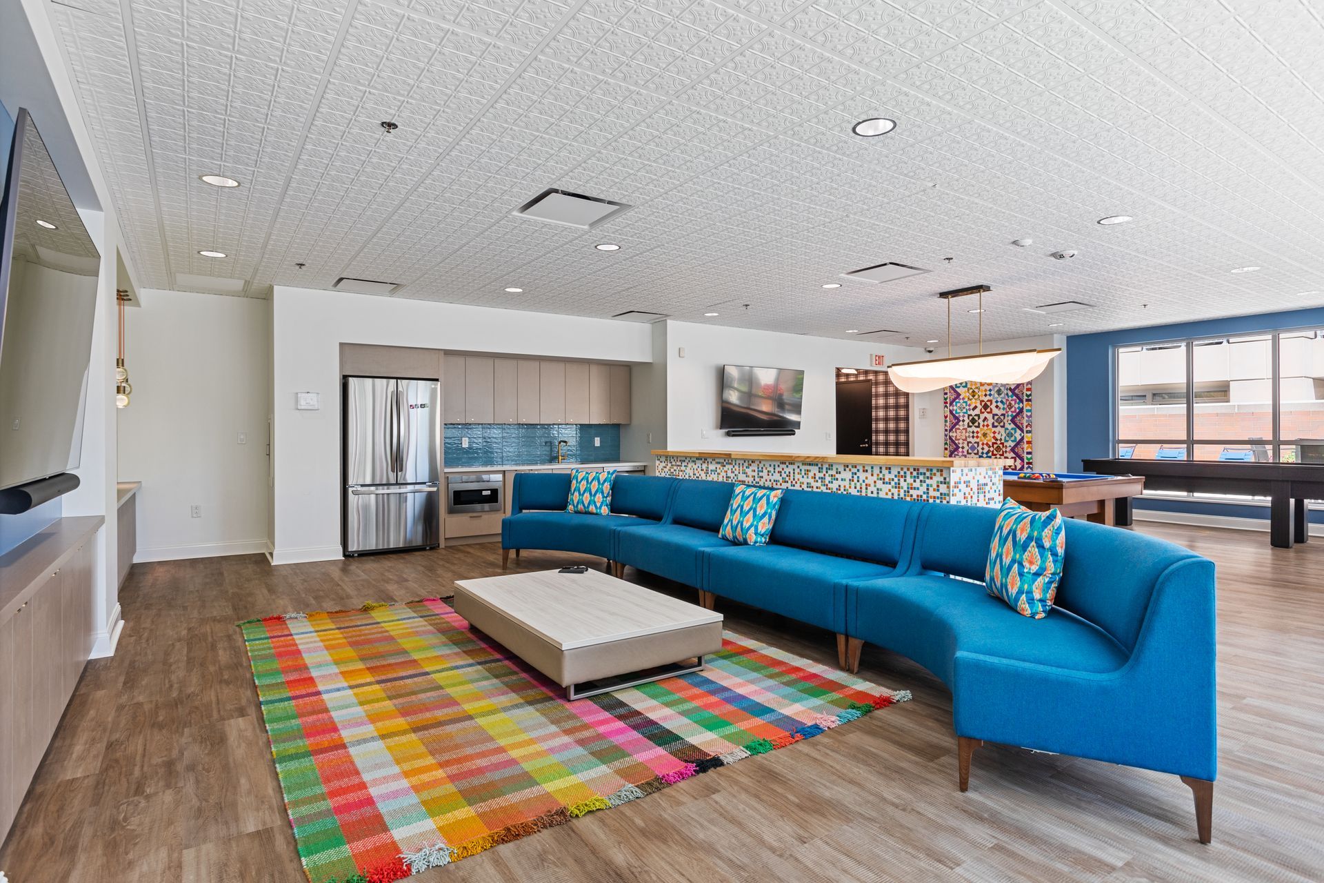 A living room with blue couches and a colorful rug