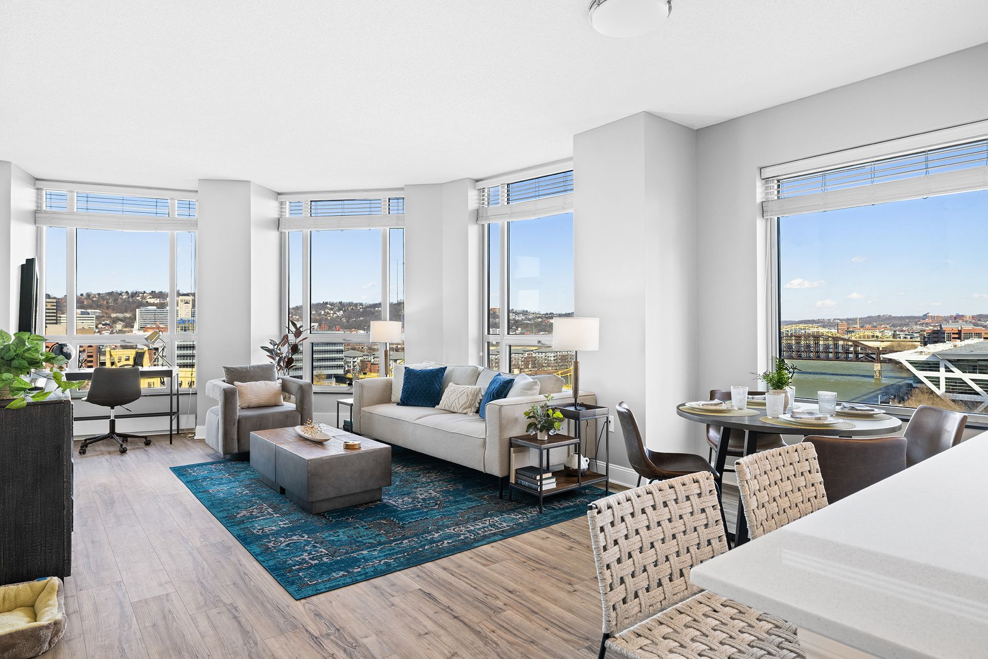 A living room with a couch , chairs , tables and a large window.