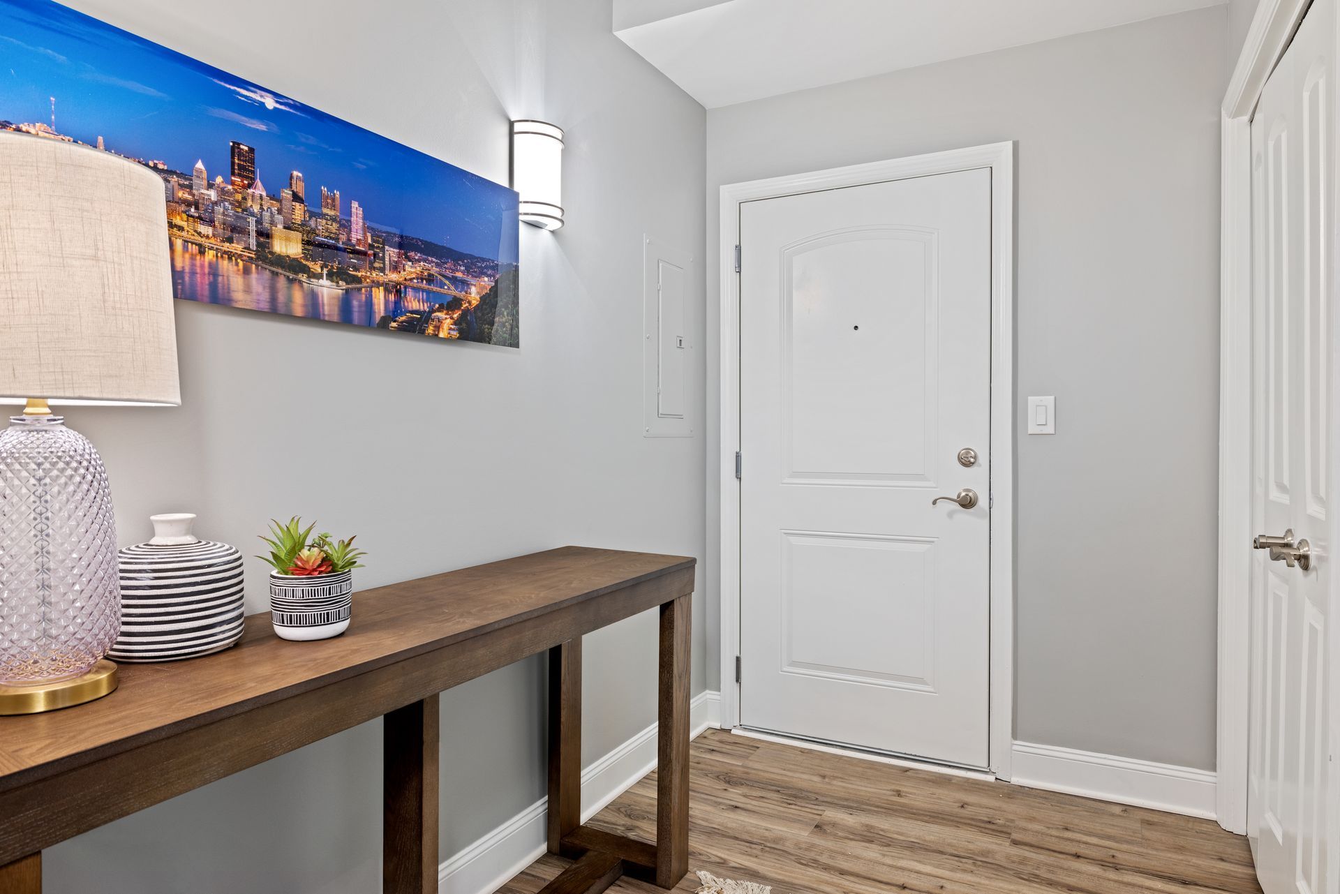 A hallway with a table and a lamp in front of a door.