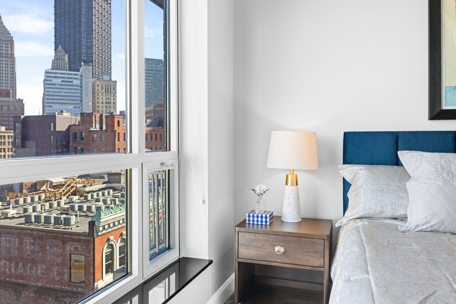 A bedroom with a bed and a lamp with a view of the city