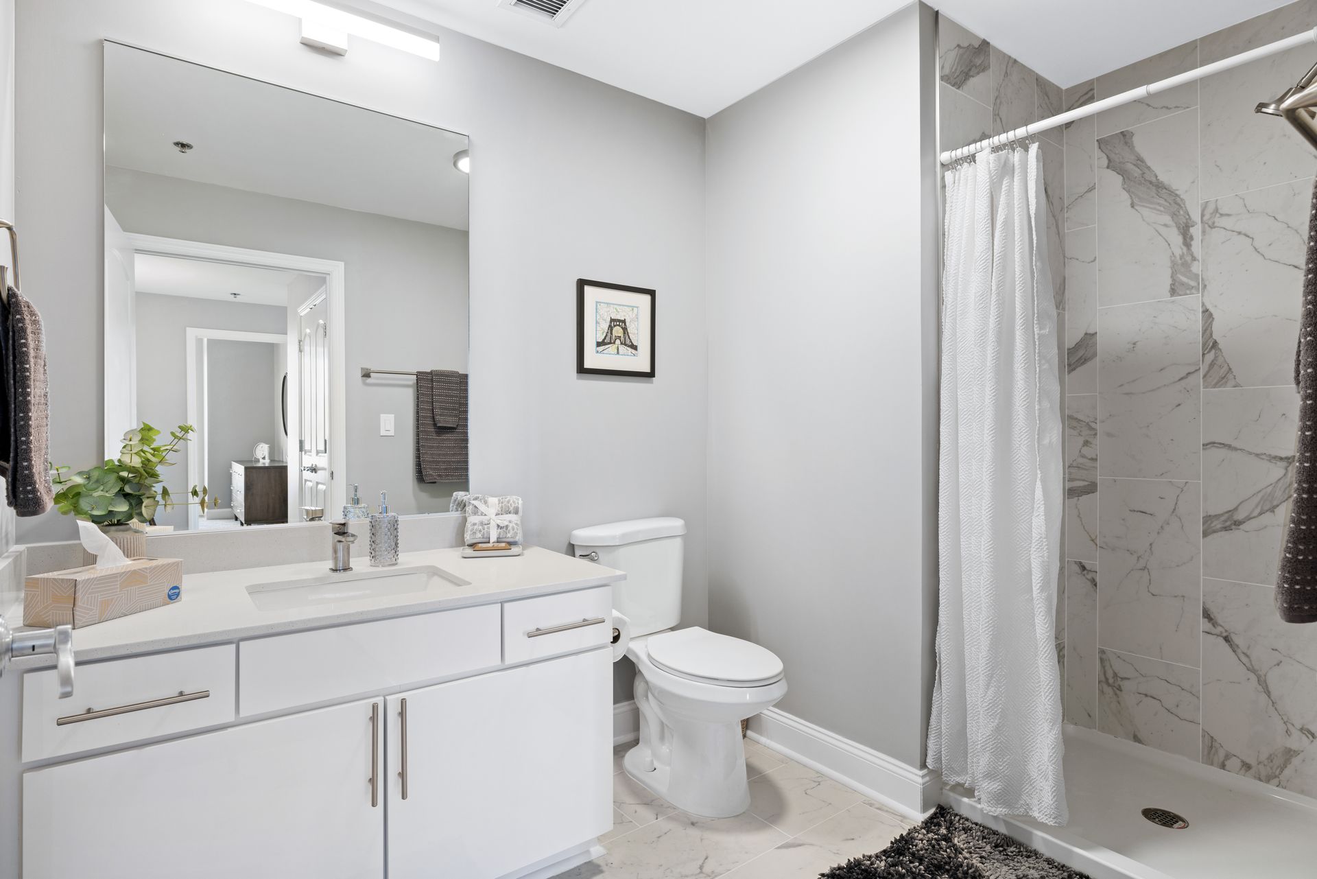 A bathroom with a toilet , sink , mirror and shower.