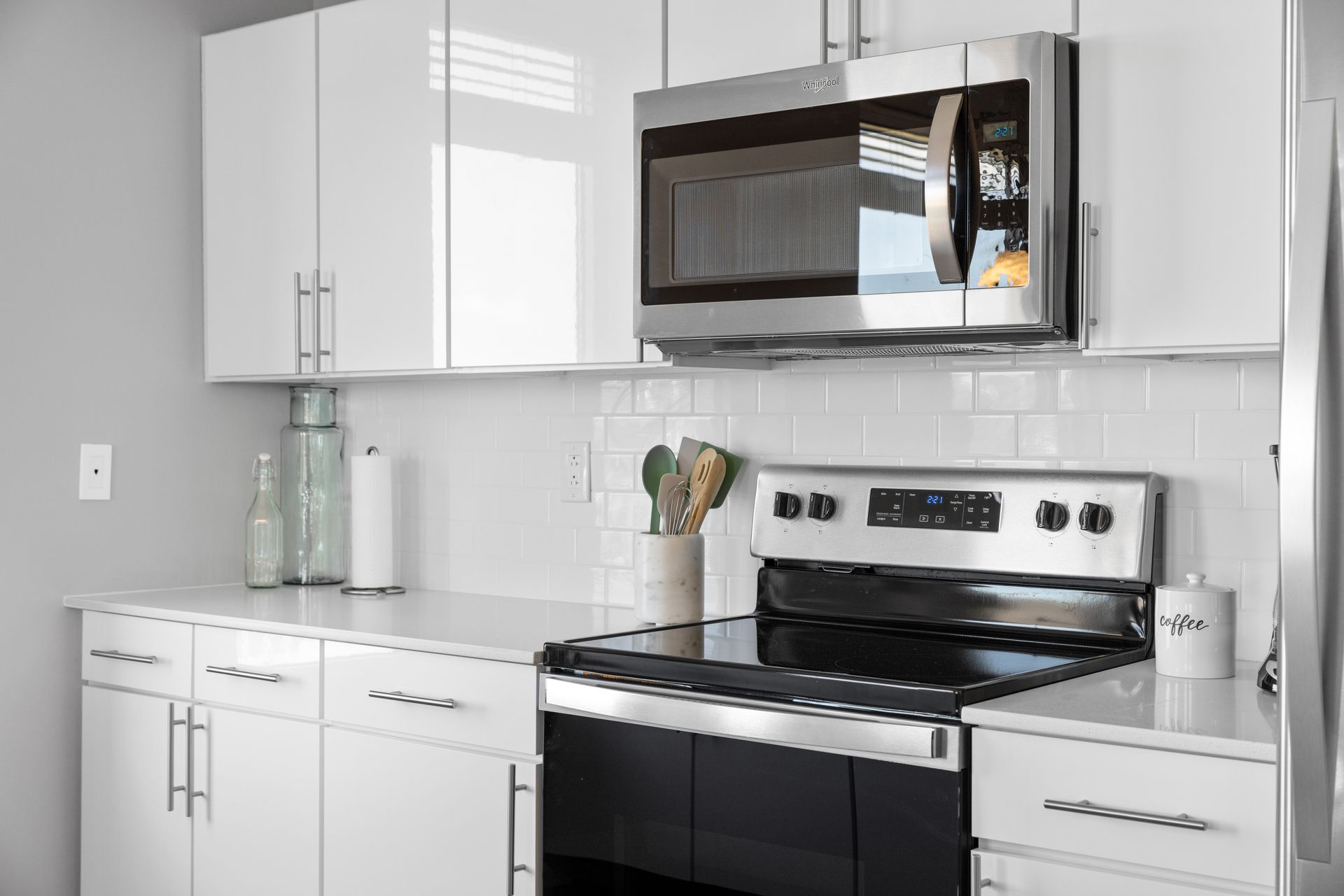 A kitchen with white cabinets , a stove , and a microwave.