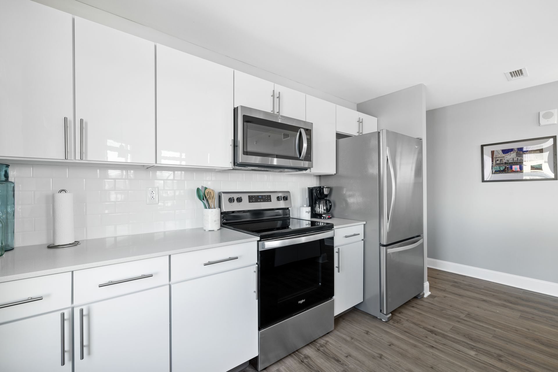 A kitchen with white cabinets , stainless steel appliances , and a refrigerator.
