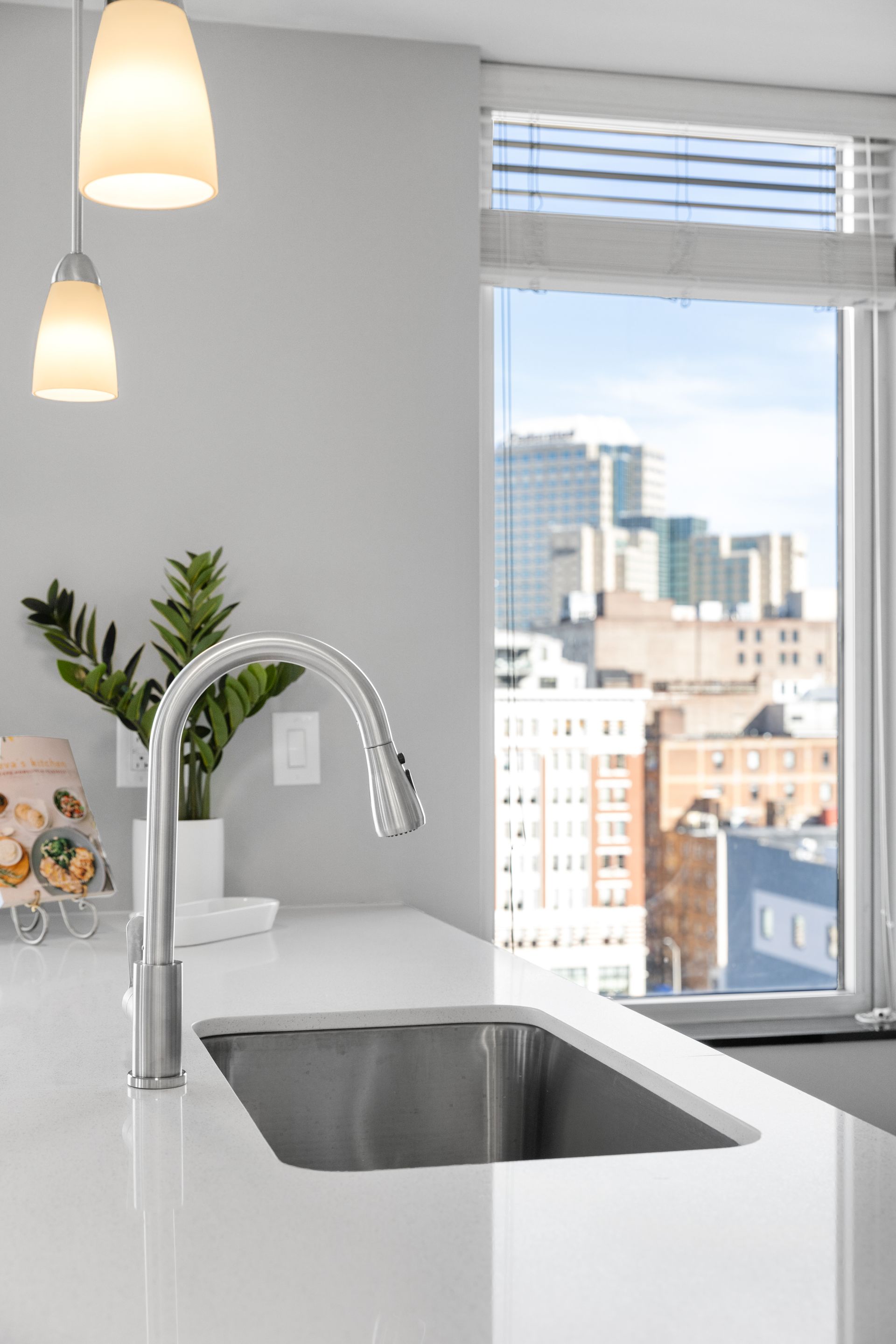 A kitchen with a sink and a window with a view of the city.