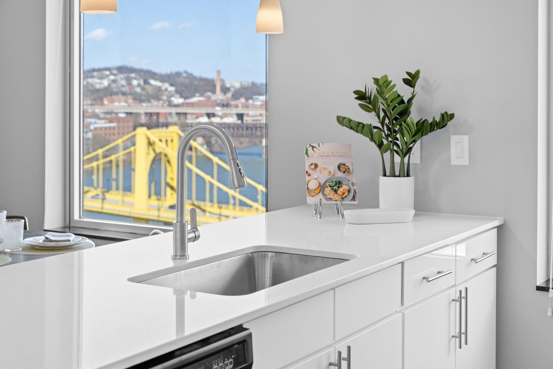 A kitchen with a sink and a window with a view of a bridge.