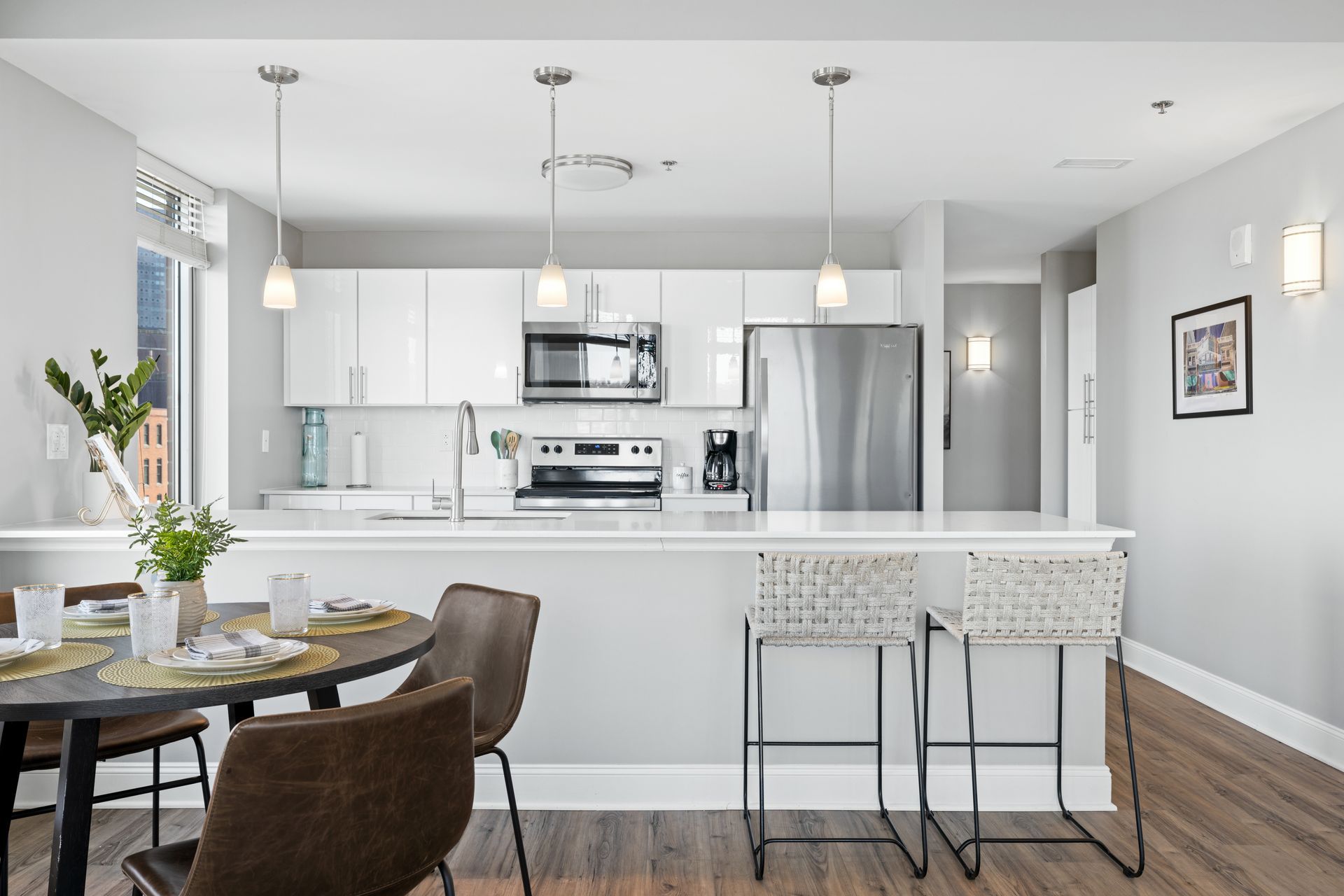 A kitchen with white cabinets , stainless steel appliances , a table and chairs.