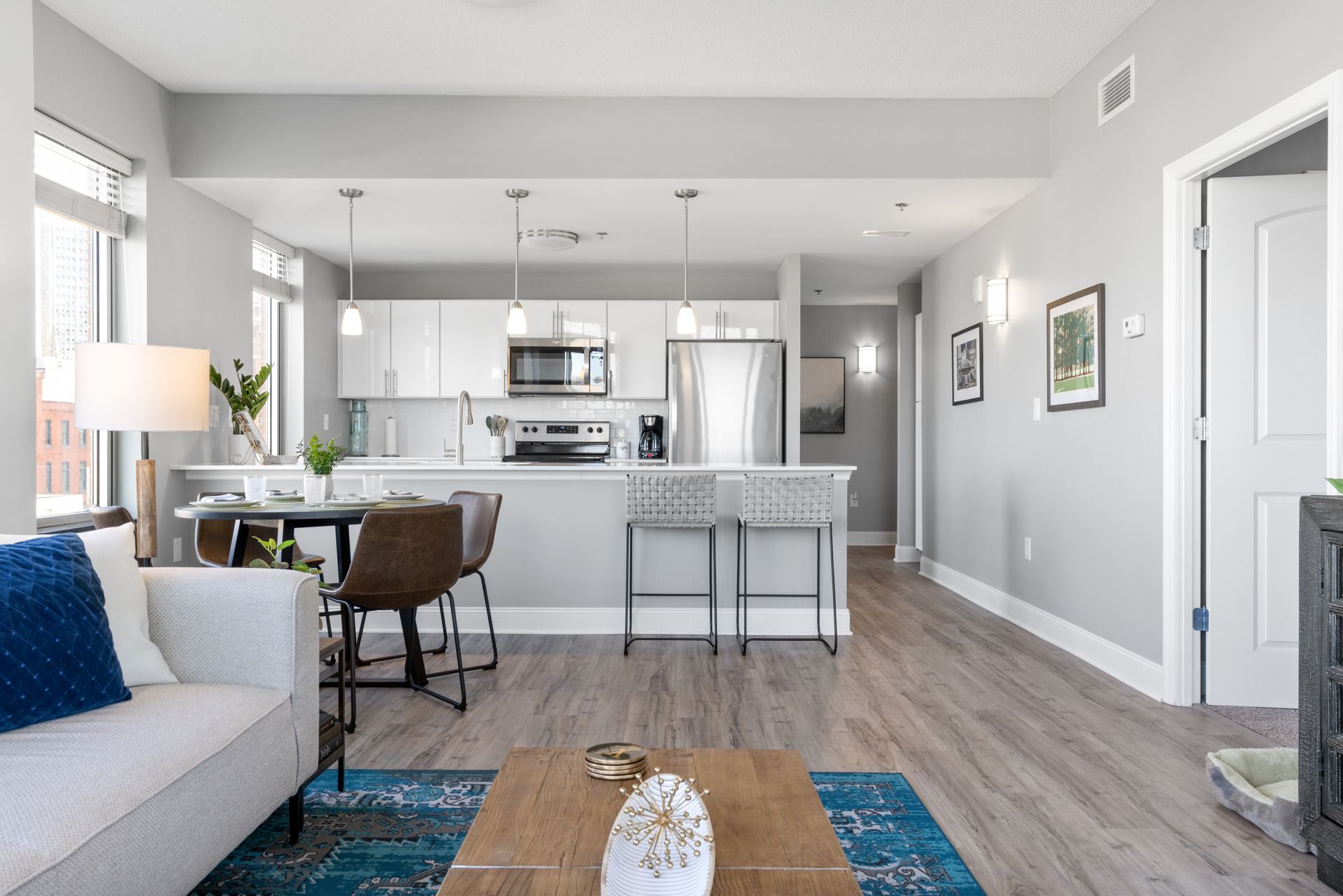 A living room with a couch , coffee table , chairs and a kitchen.