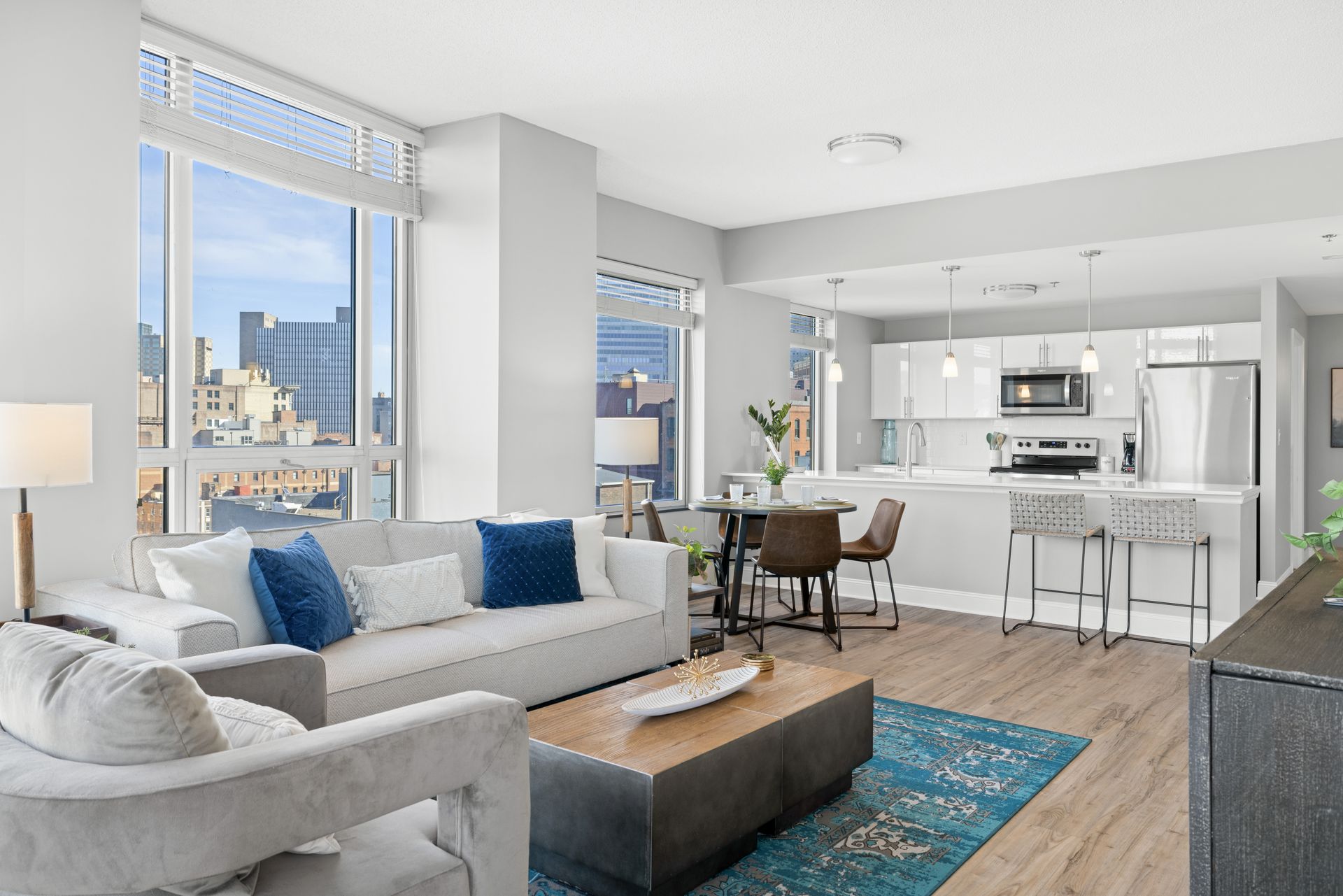 A living room with a couch , chairs , a coffee table and a kitchen.