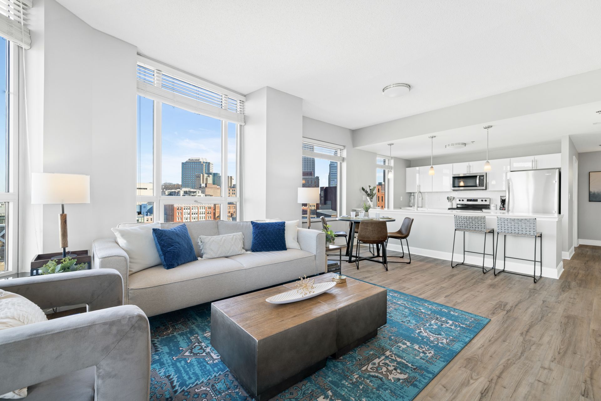 A living room with a couch , chairs , a coffee table and a rug.