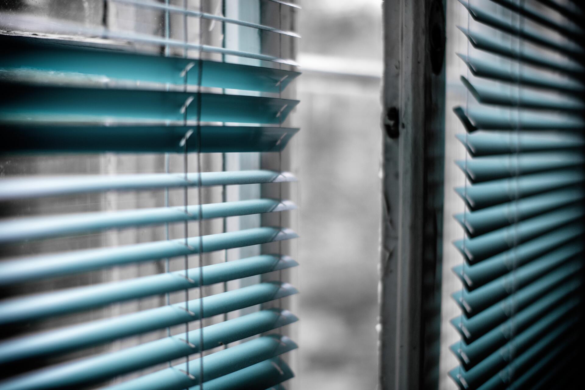 turquoise venetian blinds on a window in Townsville, partially open to filtered light