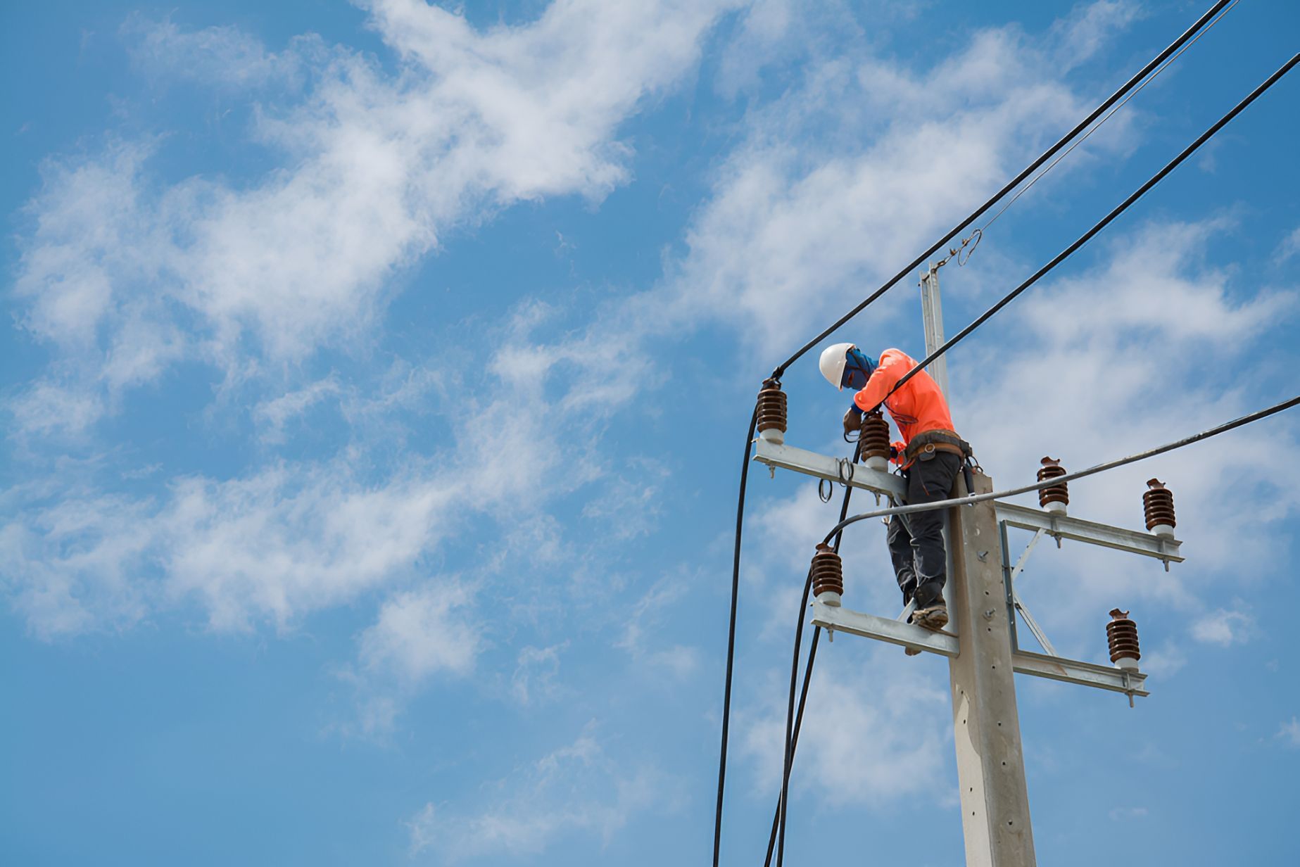 A Man Is Standing On Top Of An Electrical Pole — Entire Power Solutions In Kurri Kurri, NSW
