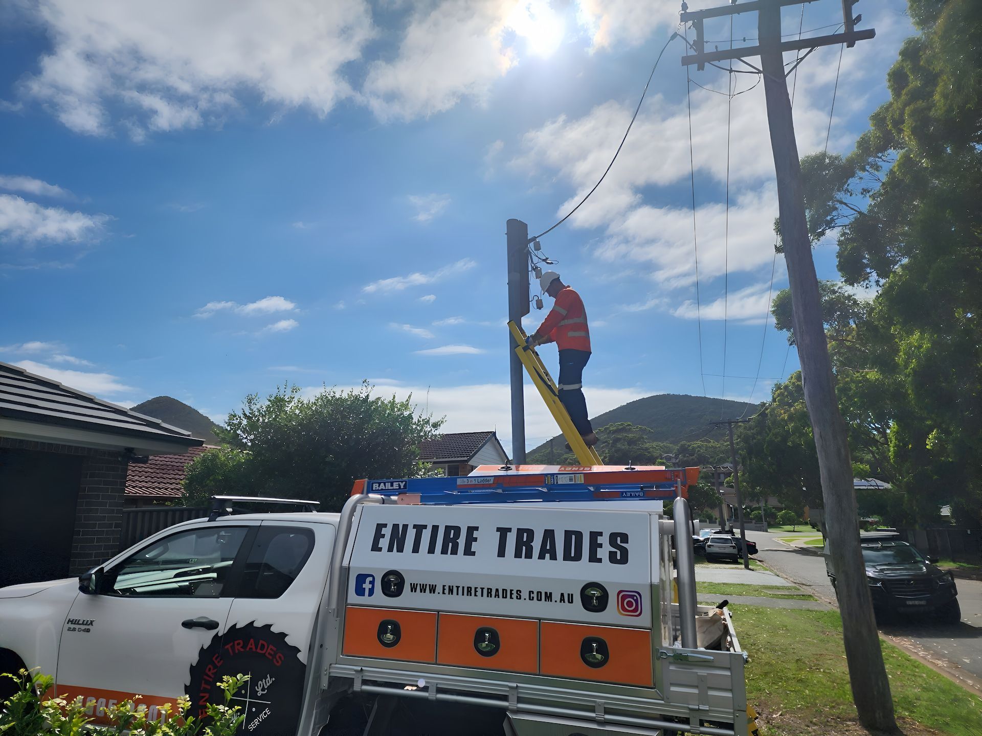 A Man In An Orange Uniform Is Working On A Powerline On A Ladder With A Work Ute In Front
— Entire Power Solutions In Branxton, NSW