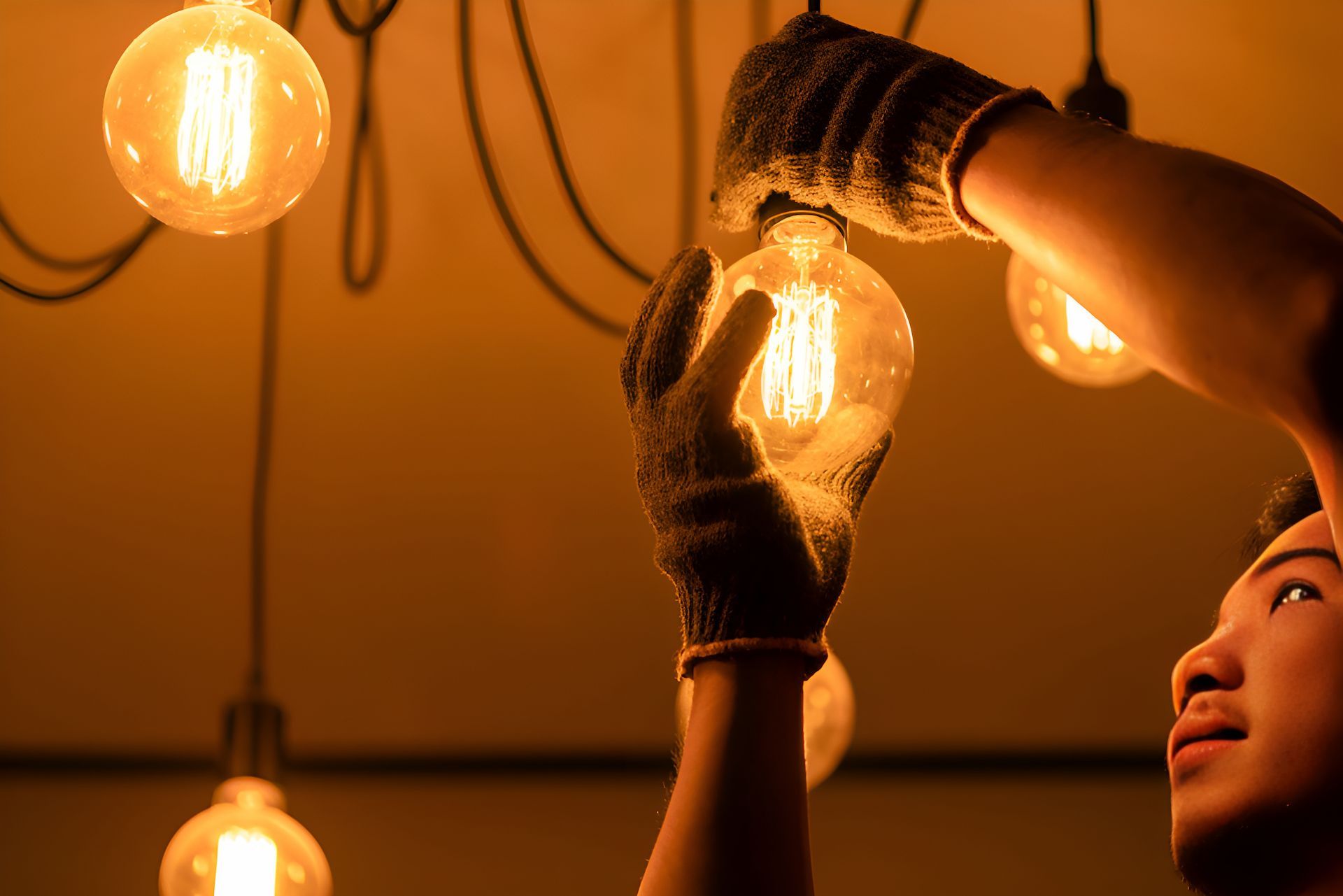 A Person Wearing Gloves Is Screwing A Lightbulb In — Entire Power Solutions In Cardiff, NSW