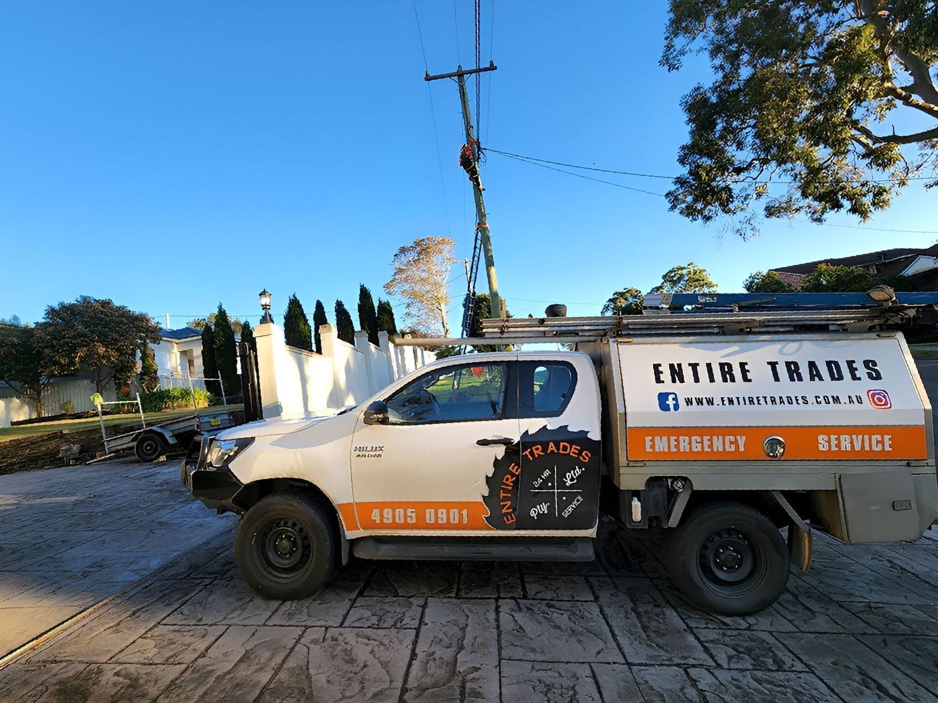 A Man In An Orange Uniform Is Working On A Powerline On A Ladder With A Work Ute In Front
— Entire Power Solutions In Singleton, NSW