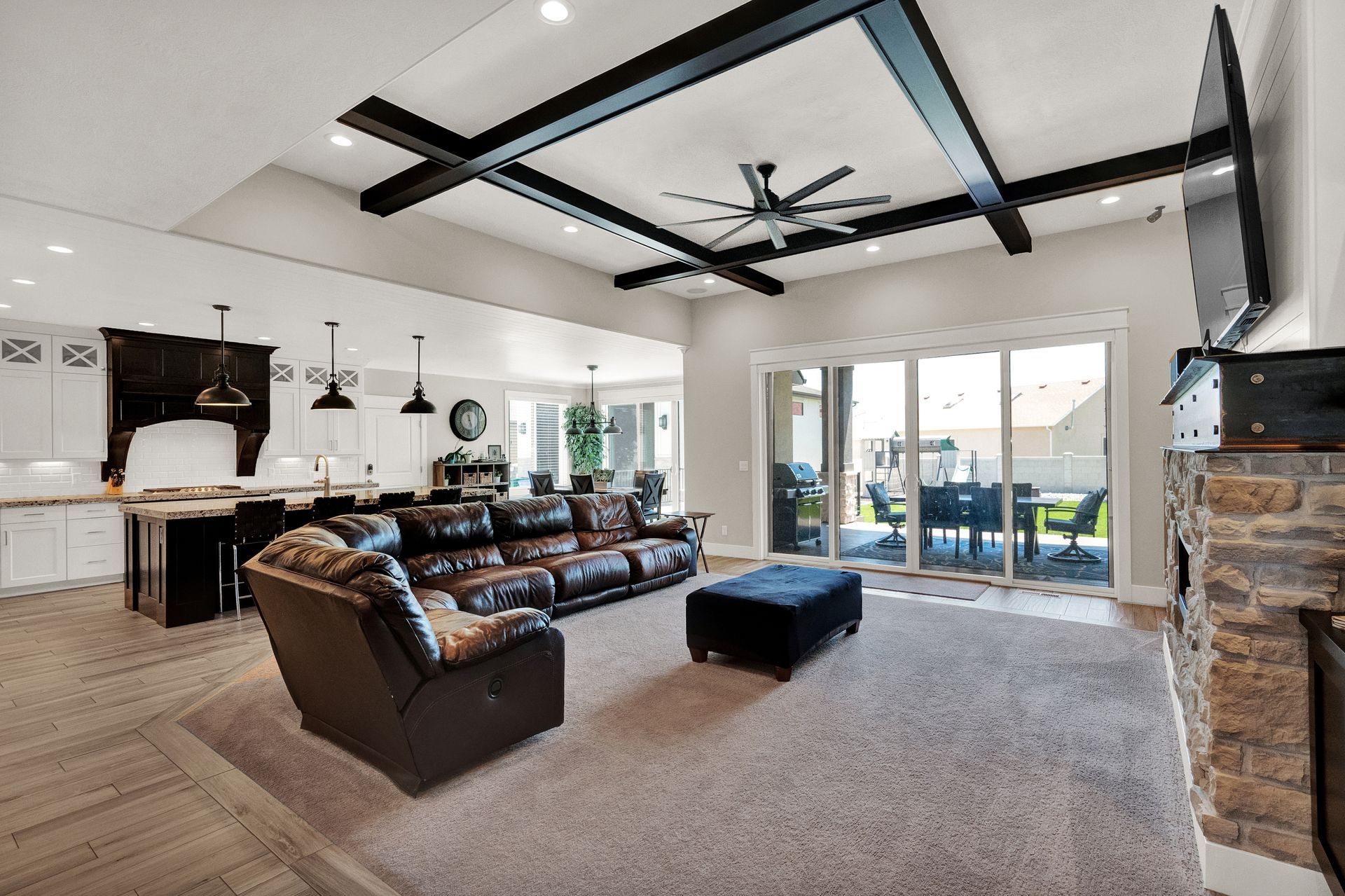 A living room with a couch , chair , ottoman and television.