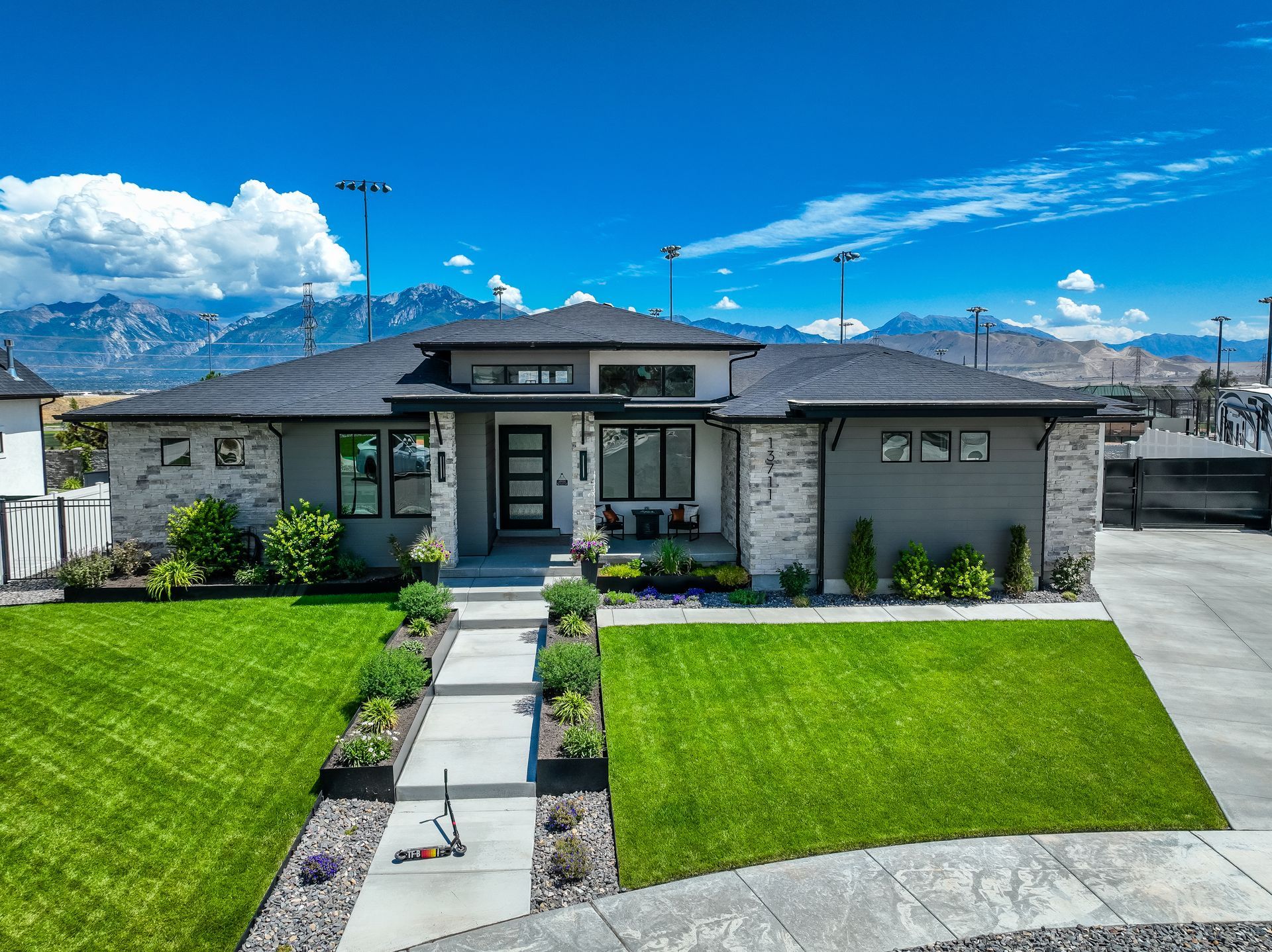 An aerial view of a house with a lush green lawn and mountains in the background.