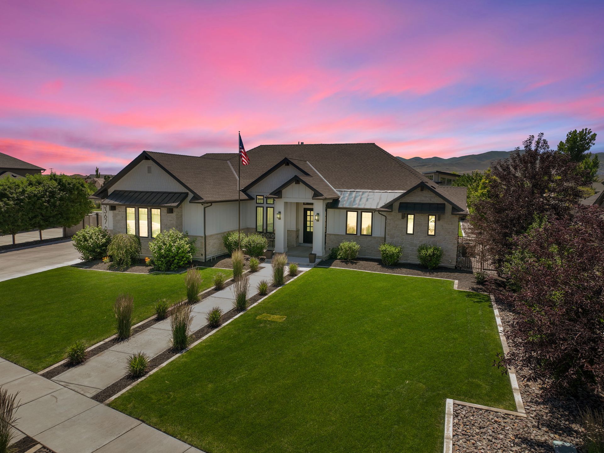 An aerial view of a house with a large lawn and a sunset in the background.