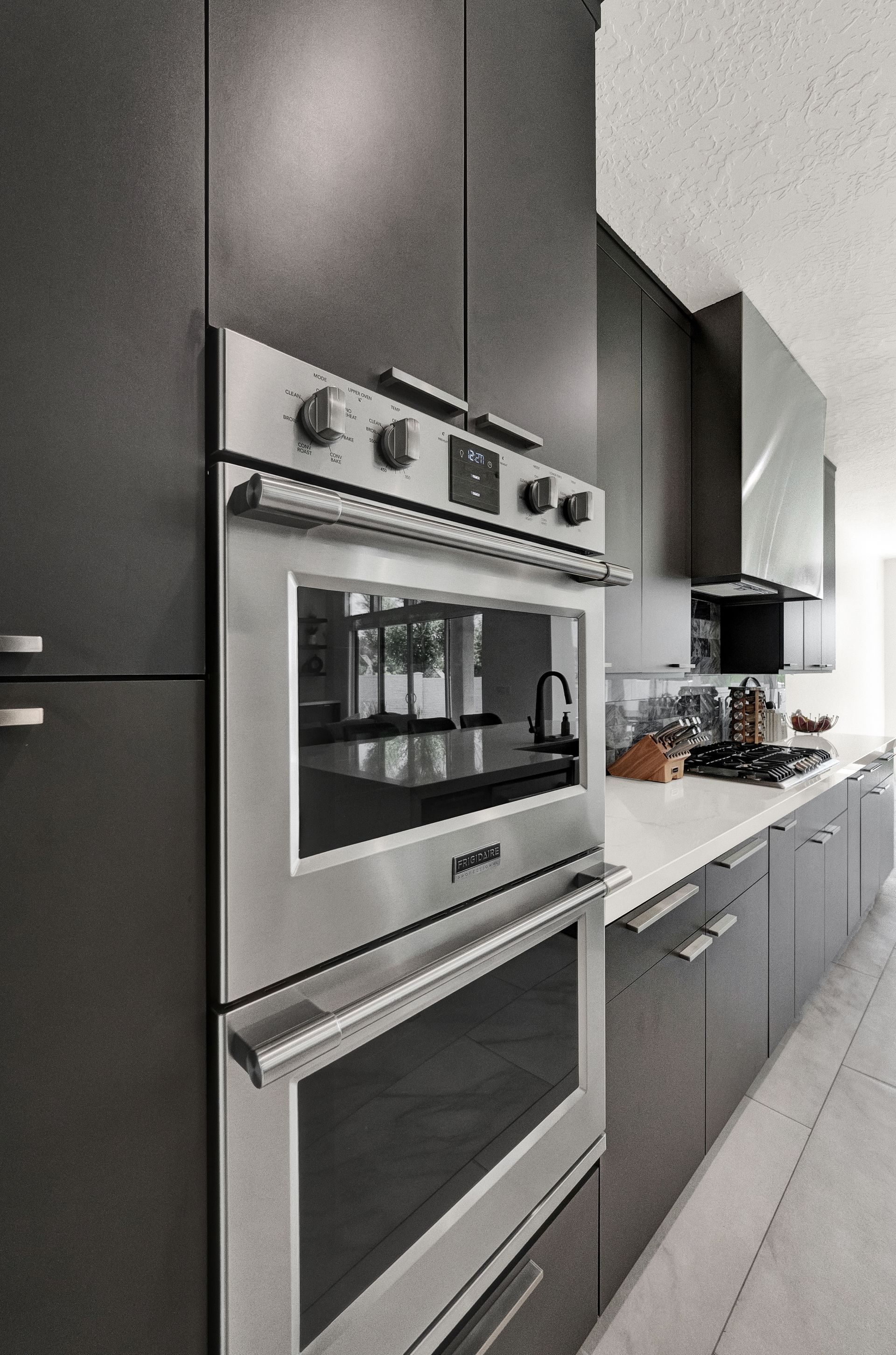 A kitchen with black cabinets and a stainless steel oven