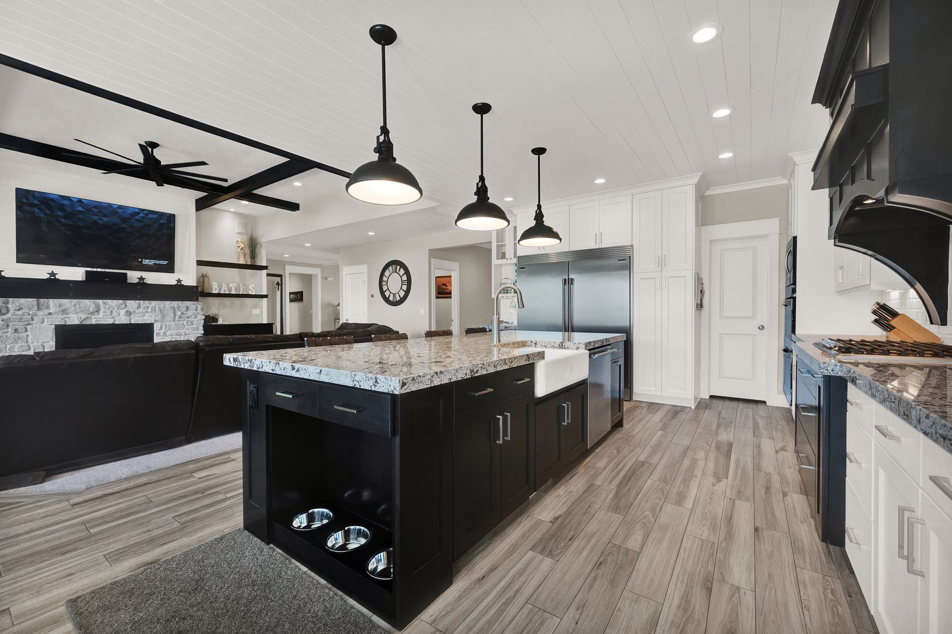 A kitchen with black cabinets and a large island in the middle.