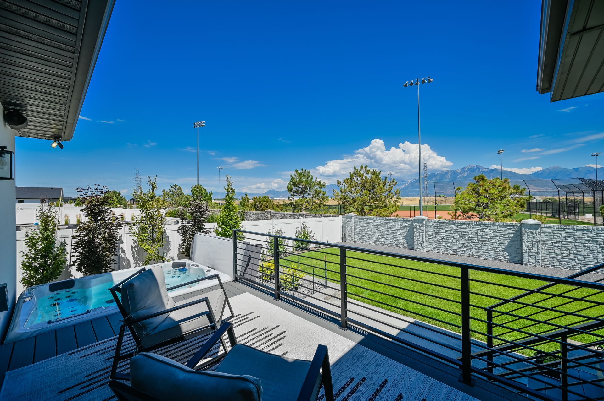 There is a balcony with a view of a field and mountains.