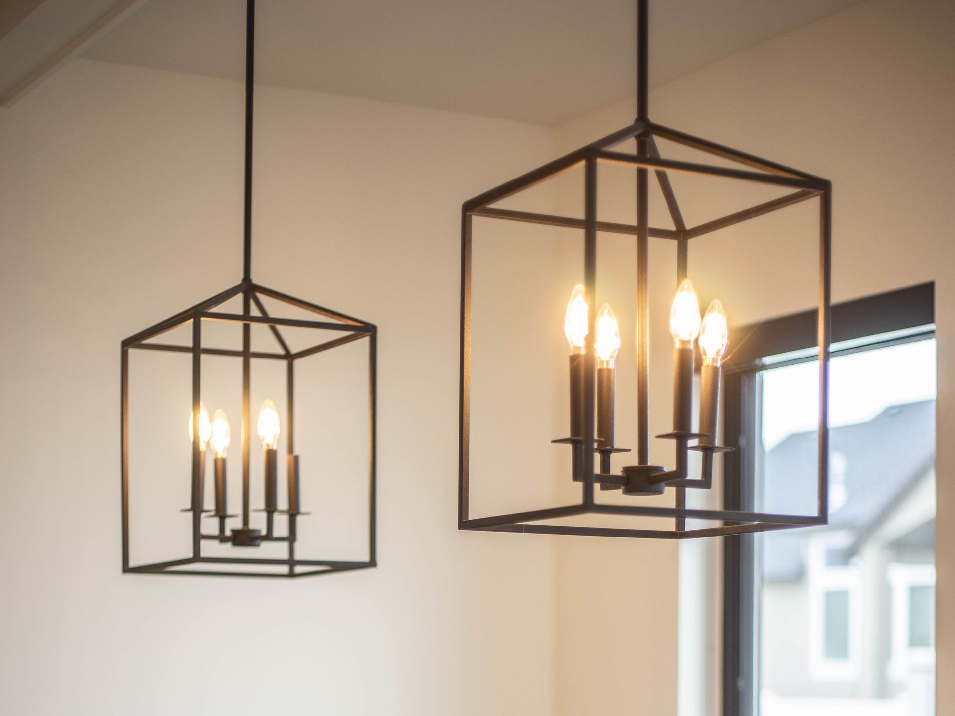 Two lanterns hanging from the ceiling with candles in them