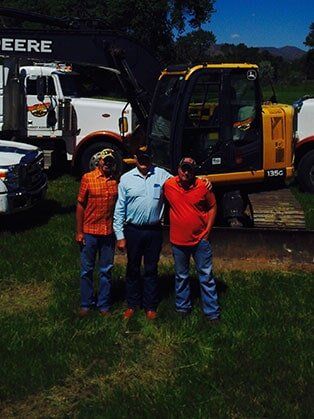 Three People in Front of Trucks — Road Grading in Laporte, CO