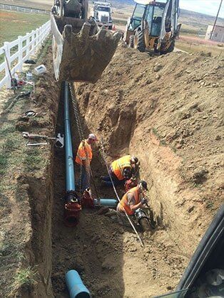 Three People Installing Pipes — Road Grading in Laporte, CO