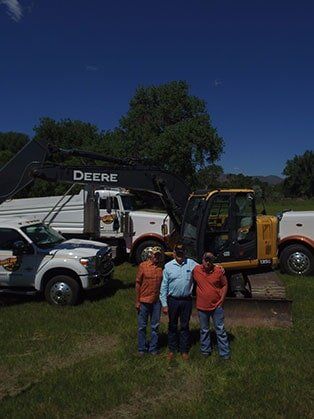 Three People with Trucks Behind — Road Grading in Laporte, CO
