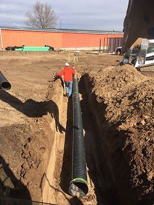 Worker Installing Pipe — Road Grading in Laporte, CO
