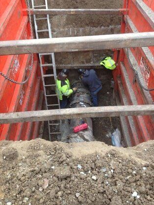 Two People Repairing Pipe — Road Grading in Laporte, CO