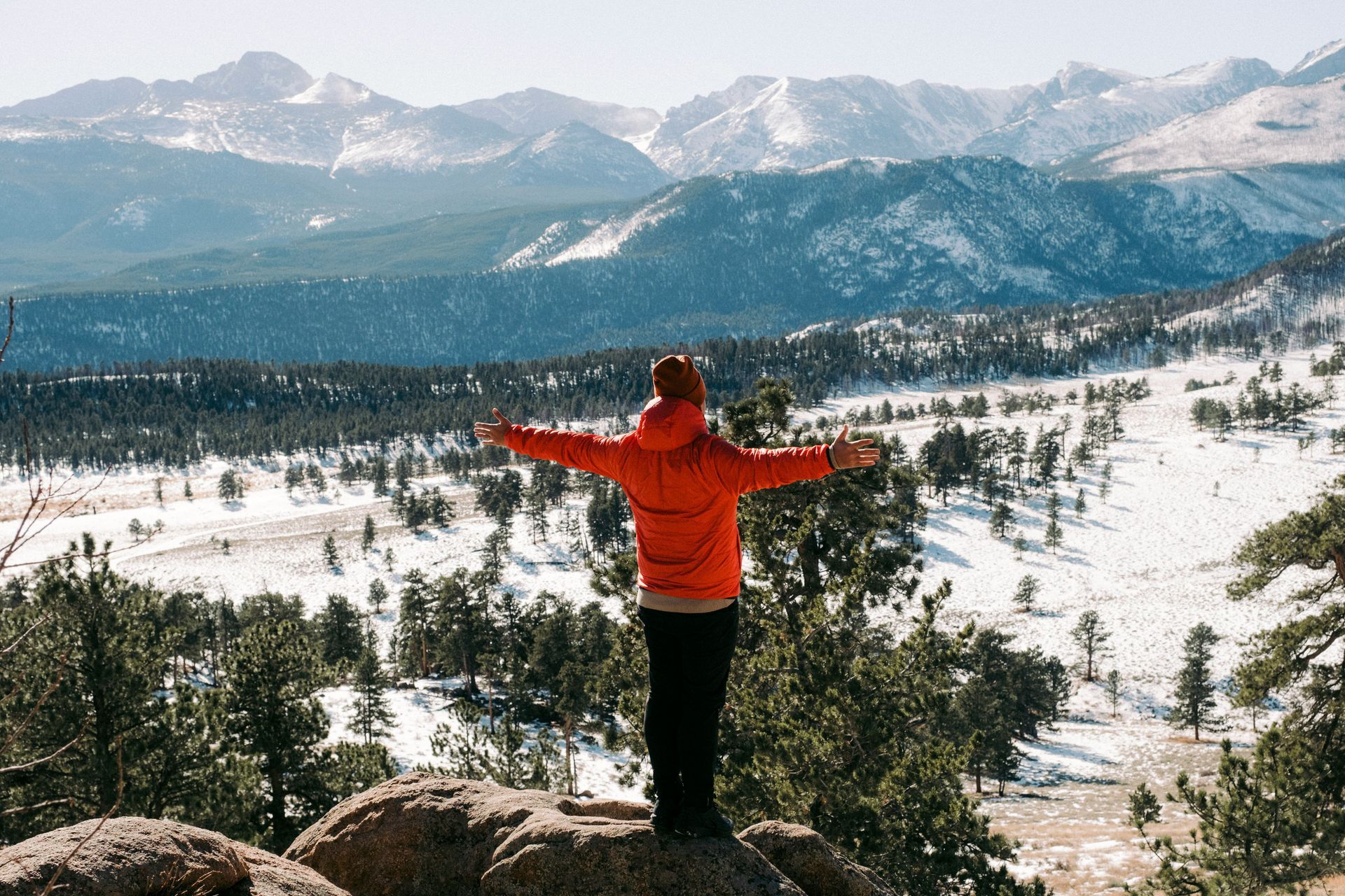 A person is standing on top of a mountain with their arms outstretched.